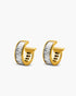Gold hoop earrings with a white stone on a light gray background